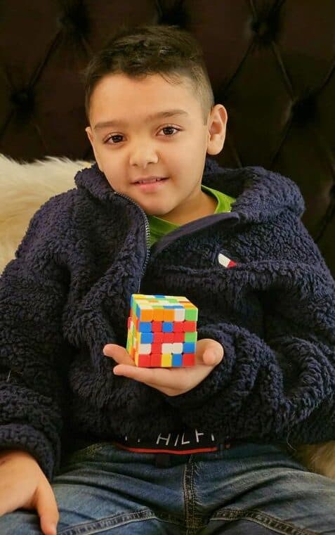 A happy Tivra Academy student holding a solved Rubik's cube